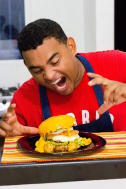 Hombre hambriento frente a hamburguesa, simbolizando desequilibrio nutricional